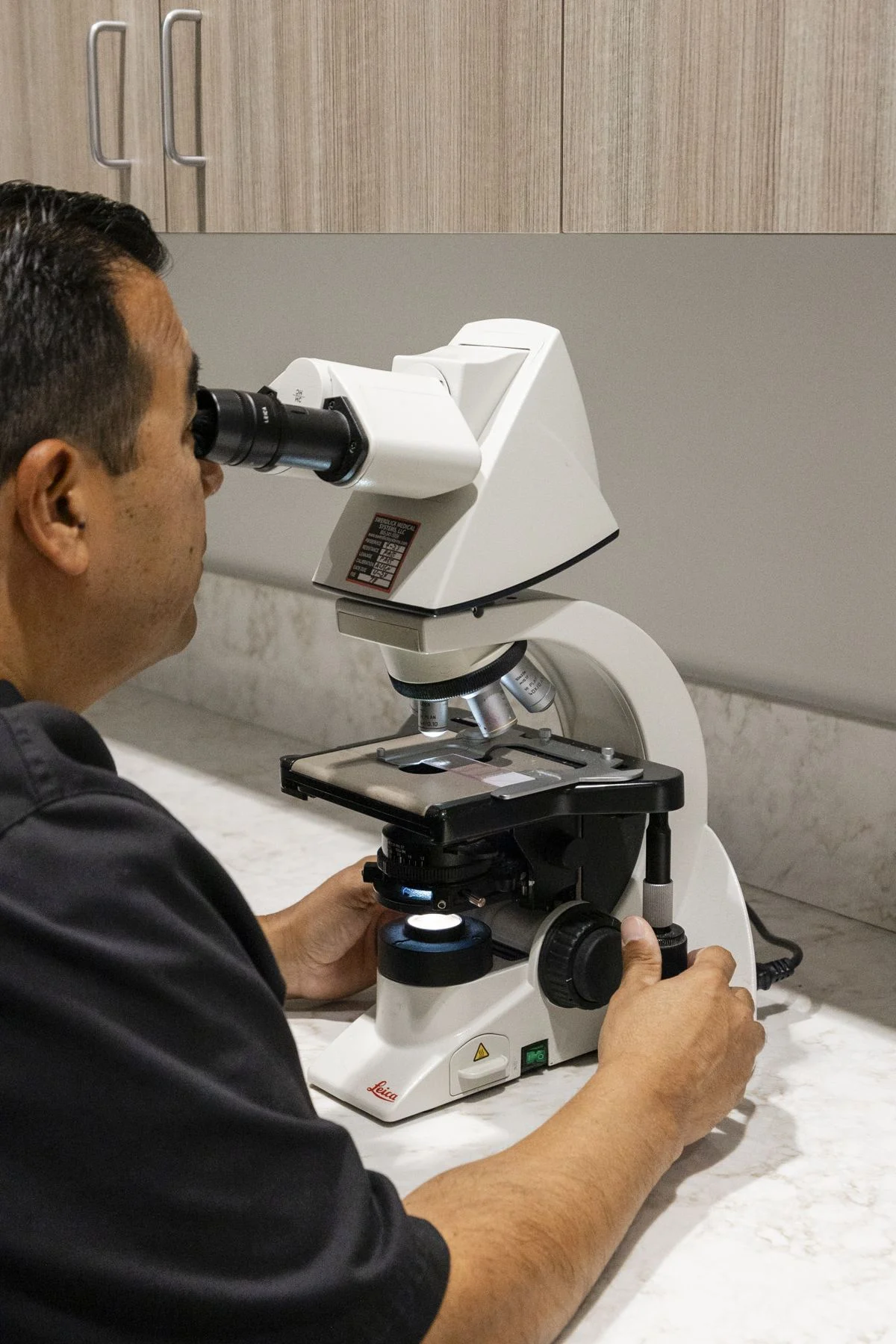 Dr. Paz reading slides at the microscope in the in-house lab