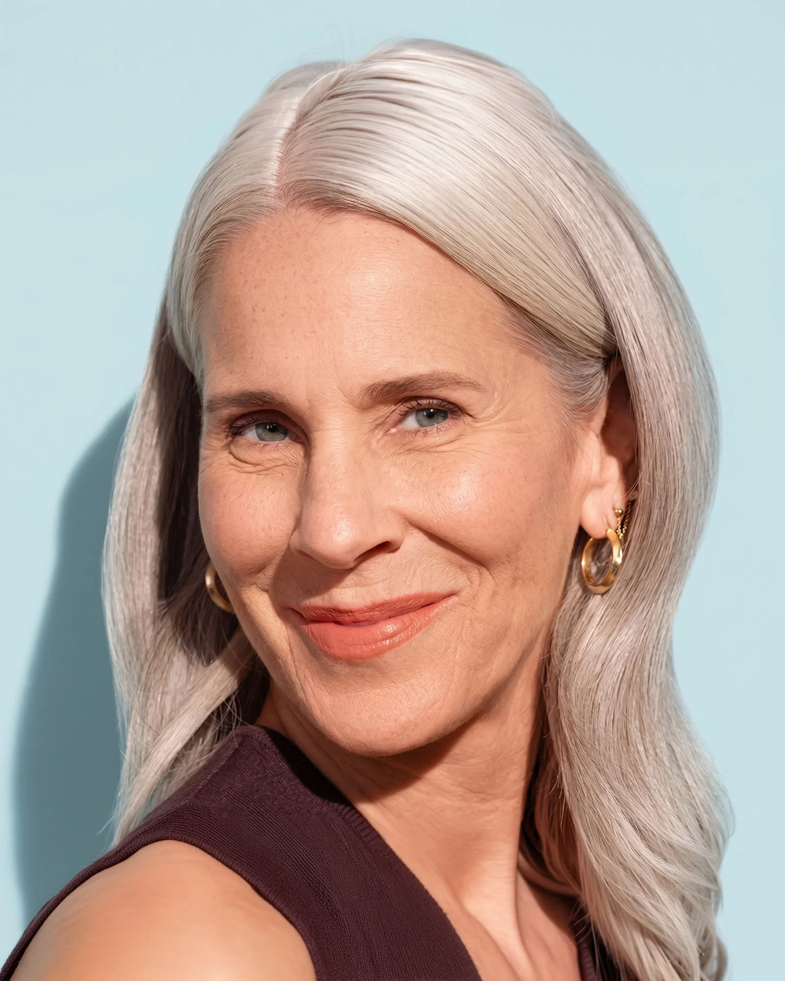 A smiling woman with long silver hair and a natural, rested look