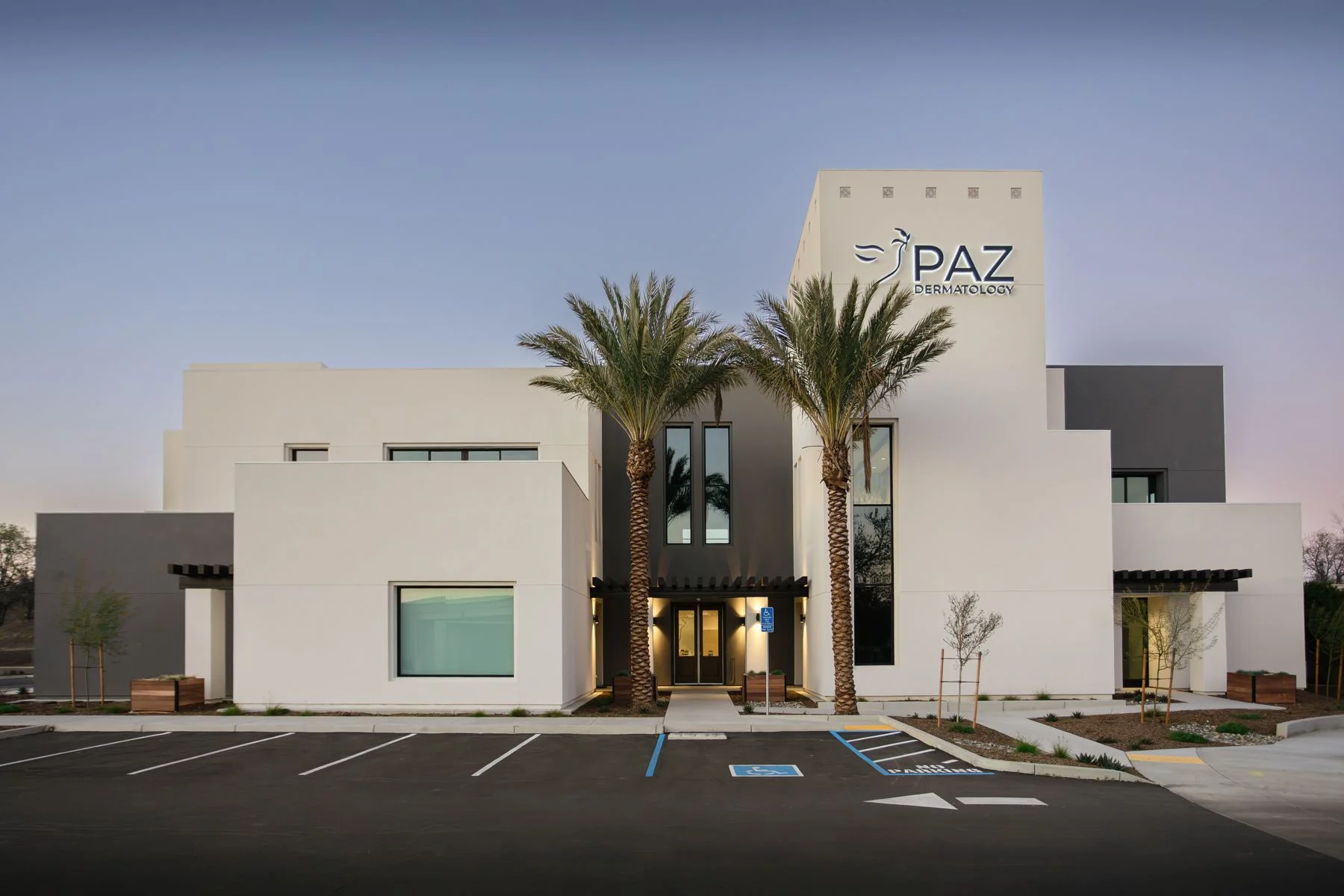 Visalia office at dusk, front with palms and the PAZ tower